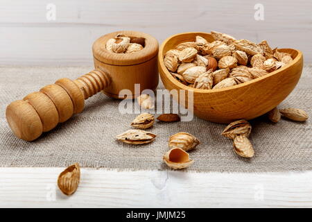 Mandeln in der Haut und Peele in braunen Schüssel auf hölzernen Hintergrund. Gesunde Ernährung. Stockfoto