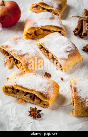 Home Herbst, Sommer, Backen, Blätterteiggebäck. Apfelstrudel mit Nüssen, Rosinen, Zimt und Puderzucker. Auf weißen Marmor Tisch. In Scheiben geschnitten, mit ingredie Stockfoto