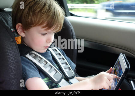 Kind während einer Autofahrt auf dem iPad spielen Stockfoto