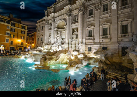 Das barocke Meisterwerk, Trevi-Brunnen in Rom an einem späten Sommerabend mit Massen von Menschen genießen alle Brunnen beleuchtet Stockfoto