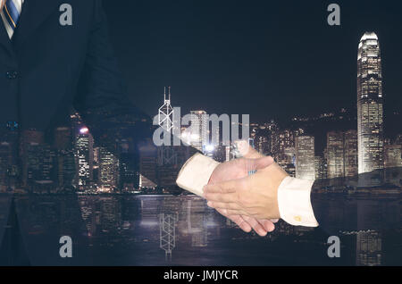 Doppelbelichtung Kaufmanns halten Geld und schüttelte die Hand auf unscharfen Stadt Hintergrund, Business-Konzept. Stockfoto