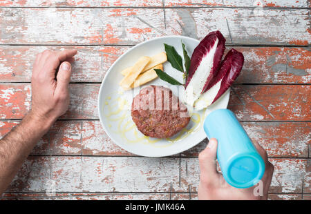 Angus Burger auf einen Teller geben, mit Olivenöl, Salat und Kartoffeln Stockfoto