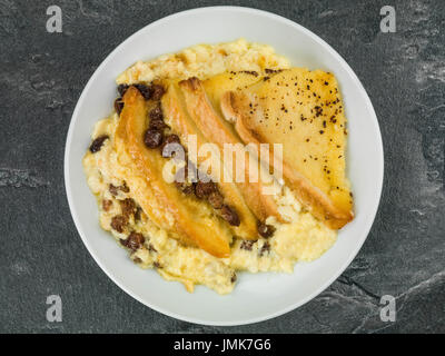 Traditionelle Brot- und Butterpudding gebackenen Nachtisch vor einem schwarzen Fliesen Hintergrund Stockfoto