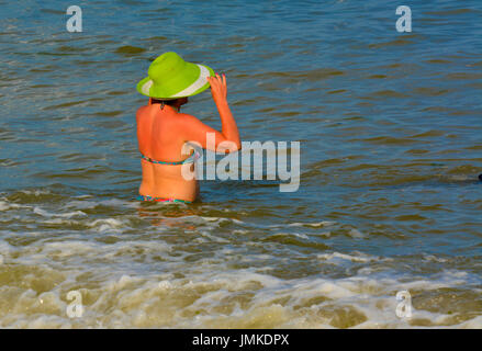 Der Rottweiler Hund und Herrin im Wasser am Strand spielen mit einem Spielzeug in Form eines Ringes. Juli 2017, Odessa, Ukraine Stockfoto