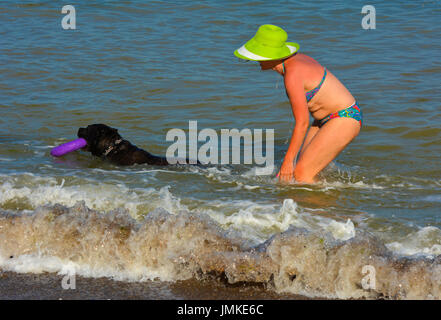 Der Rottweiler Hund und Herrin im Wasser am Strand spielen mit einem Spielzeug in Form eines Ringes. Juli 2017, Odessa, Ukraine Stockfoto