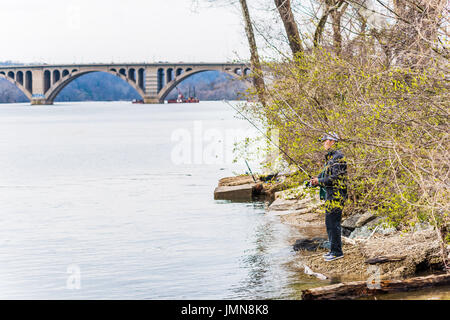 Washington DC, USA - 20. März 2017: Person Angeln am Flussufer in Georgetown mit Key Bridge im Potomac River Stockfoto