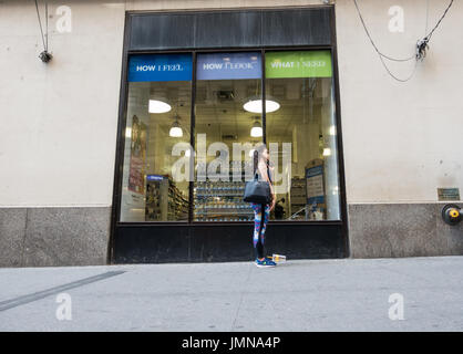 Junge Latino-Frau am Telefon beim stehen auf dem Bürgersteig an der vom Fensterrand / store in New York City Stockfoto