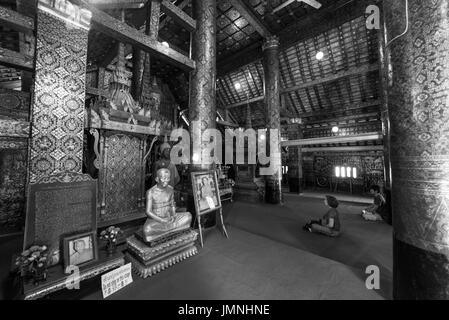 LUANG PRABANG, LAOS - 11. März 2017: schwarz / weiß-Bild von Menschen, die beten innerhalb Wat Xieng Thong, buddhistische Tempel befindet sich in der Stadt Luang Prab Stockfoto