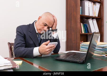 Der Mann am Schreibtisch, betrachten Sie Ihre i Pad/Tablet, in seinem Büro. Stockfoto