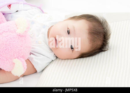 Porträt von adorable Babymädchen auf dem Bett liegend Stockfoto