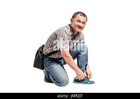 Porträt eines glücklichen Reifen Scott Hemd und blaue Jeans seine Schuhe zu binden. Isolierte voller Länge auf weißem Hintergrund mit textfreiraum und Clipping-pa Stockfoto