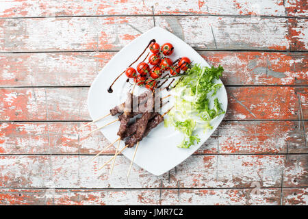 Arrosticini Fleisch in eine Schüssel mit Salat und Tomaten auf dem Tisch Stockfoto