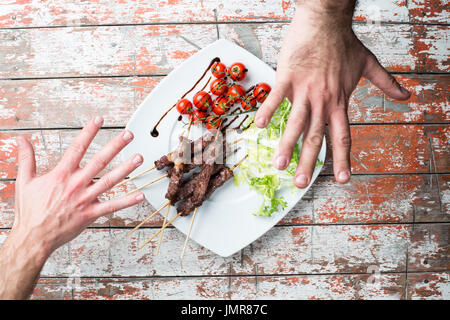 Arrosticini Fleisch in eine Schüssel mit Salat und Tomaten auf dem Tisch Stockfoto