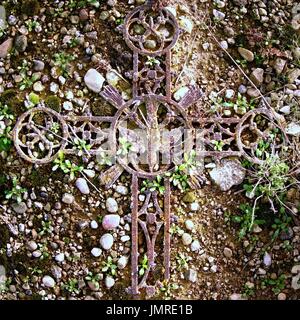 Gebrochene Eisen rustikal Kruzifix auf alten bemoosten Grabstein. Verlassene Symbol der Religion. Stockfoto