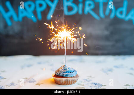 leckere Cupcake mit Wunderkerze weiß, Großaufnahme auf schwarzem Hintergrund Stockfoto