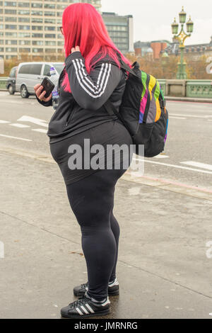 Eine übergewichtige Frau mit roten Haaren, halten eines Handys auf Westminster Bridge, London. Stockfoto