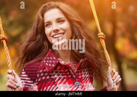 Frau auf einer Schaukel in einem herbstlichen park Stockfoto