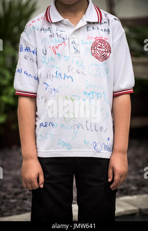 Jungen Junior Schüler trägt ein weißes Hemd von all seinen Freunden am Ende der Schule unterzeichnet im Sommersemester. Newquay, Cornwall. Stockfoto