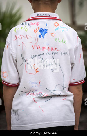 Jungen Junior Schüler trägt ein weißes Hemd von all seinen Freunden am Ende der Schule unterzeichnet im Sommersemester. Newquay, Cornwall. Stockfoto