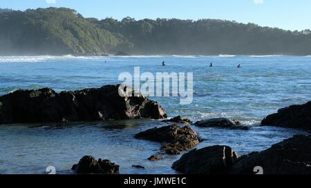 Blick aufs Meer, Felsen, Schwimmer oder Surfer, Wellen und Hügeln in Australien Stockfoto