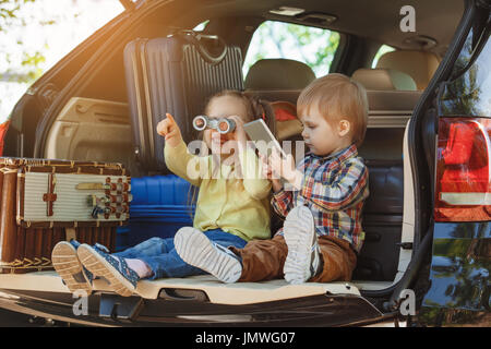 Auto-Familie zusammen reisen Sie, Bruder und Schwester sitzen im Kofferraum Stockfoto