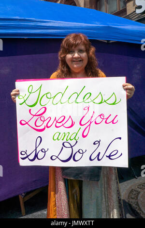 Ein Teilnehmer mit roten Haaren am Witchsfest 2017 hielt eine Karte reading "Göttin Liebe dich und das tun wir." Auf Astor Place in Manhattan, New York City. Stockfoto