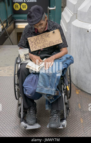 Ein Diabetiker senior Mann in einem Rollstuhl mit einem Schild Hereinholen Spenden ein Buch zu lesen. Am Broadway im Abschnitt Soho in Manhattan, New York CIty. Stockfoto