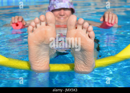 Cool bleiben! Frau schwimmt auf zwei Poolnudeln in einem Schwimmbad. Einfach nur chillen. Stockfoto