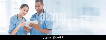 Digital Composite Ärzte betrachten eine Tablette vor blauem Hintergrund Stockfoto