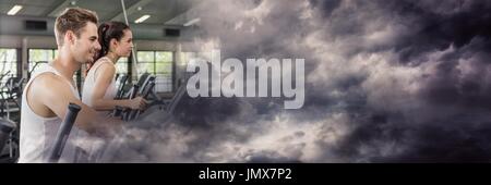 Digitalen Verbund von Mann und Frau auf cross-Trainer mit stürmischen Wolke Übergang Stockfoto