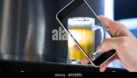 Digitalen Verbund aus beschnitten Hand unter Bild von Bierglas in Bar Stockfoto