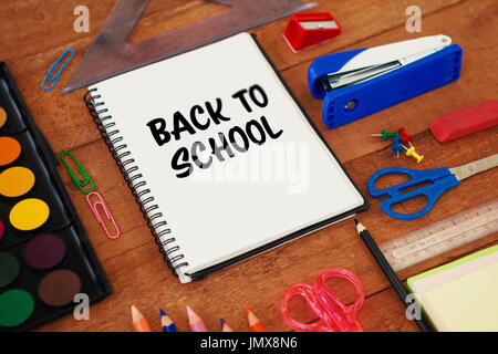 Zurück zu Schule Text auf weißem Hintergrund gegen Schulmaterial auf Holztisch Stockfoto
