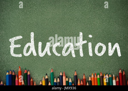 Bildung-Text auf weißem Hintergrund gegen Draufsicht Buntstifte auf grauen Tisch Stockfoto