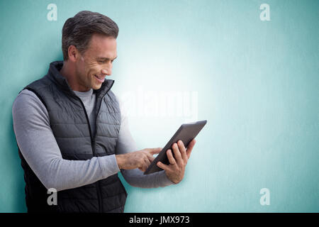 Reifer Mann, Surfen im Internet mit seinem Tablet vor blauem Hintergrund Stockfoto