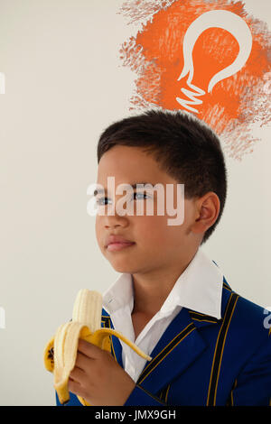 Digitalen zusammengesetztes Bild der Glühbirne auf blaue Sprühfarbe gegen Schüler essen Bananen vor weißem Hintergrund Stockfoto