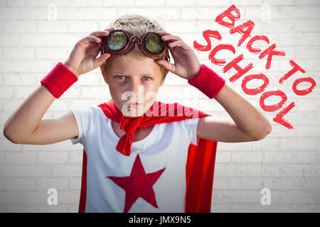 Kleiner Junge tat, als Superheld gegen weiße Wand Stockfoto