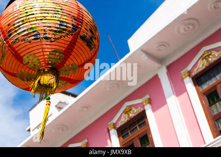 Rote chinesische Laterne gegen den blauen Himmel und rosa Fassade des sino-portugiesischen Stadthaus in Soi romanee Altstadt, Phuket, Phuket, Thailand Stockfoto