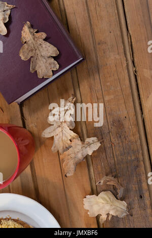 Aufwand für die Kaffeetasse, Herbstlaub und Tagebuch auf Holztisch Stockfoto