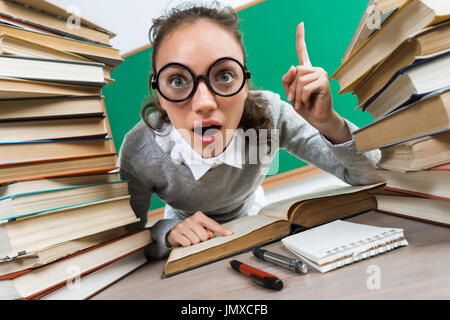 Studierende/r, die gute Idee, Finger oben zeigt. Foto von erstaunt junges Mädchen mit Brille rund um Bücher. Bildungskonzept Stockfoto