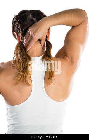 Rückansicht des weiblichen Athleten massiert Hals stehend vor weißem Hintergrund Stockfoto