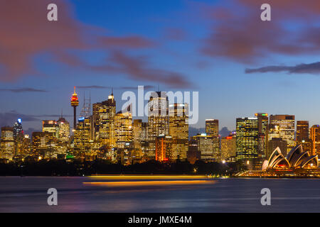 Skyline von Sydney Hafen nach Sonnenuntergang mit Bewegung verwischt Fähre vorbei. New South Wales, Australien. Stockfoto