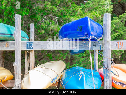 verschiedene farbige Kajaks auf einem hölzernen Gestell bei klarem Wasser Strand im Osten Hampton, ny Stockfoto