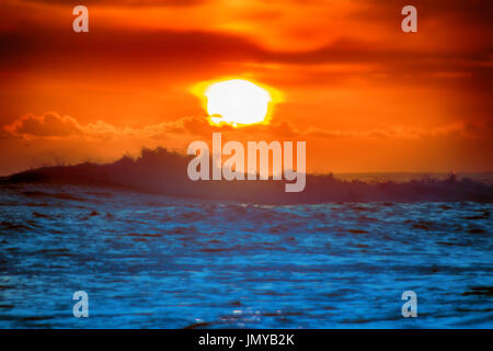 gefüllt mit Farben der marine tropischen Sonnenuntergang. Wave Splash ist am Strand gerollt. Stockfoto