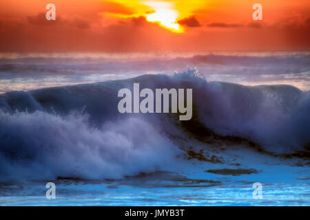 gefüllt mit Farben der marine tropischen Sonnenuntergang. Wave Splash ist am Strand gerollt. Stockfoto