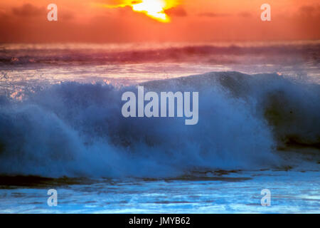 gefüllt mit Farben der marine tropischen Sonnenuntergang. Wave Splash ist am Strand gerollt. Stockfoto