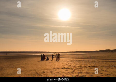 Silhouetten einer Familie bei Sonnenuntergang am Camber Sands Beach bei Ebbe, East Sussex, England Stockfoto