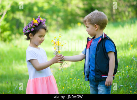 kleiner Junge mit Blumen für ein kleines Mädchen Stockfoto