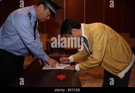 (170729)--Peking, 29. Juli 2017 (Xinhua)--Ren Biao (R) Zeichen auf seiner Verhaftung rechtfertigen in Beijing Capital International Airport in Peking, Hauptstadt von China, 29. Juli 2017. Ren Biao, einer der meistgesuchten flüchtigen Chinas, hat kehrte nach China zurück und stellte sich in der Polizei, die Anti-Korruptions-Behörde sagte am Samstag. Ren, 44, ehemalige "tatsächliche Mehrheitsaktionär" Daluo Energie beliefert Unternehmen in Ost-China Jiangsu Provinz, floh in die karibische Nation von St. Kitts und Nevis im Januar 2014, nachdem er beschuldigt betrügerisch Kredite zu erhalten und die Herstellung finanzielle Rechnungen, Acc Stockfoto