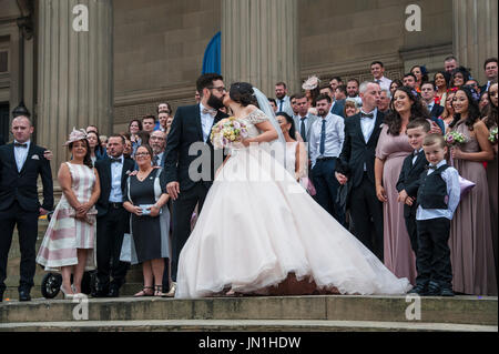 Liverpool. 29.. Juli 2017: Pride Festival in Liverpool verfügt über 2 Stufen der Unterhaltung auf St. Georges Plateau und William Brown Street in der Nähe der Walker Art Galery wo die Show der Kunst und Fotografie "Coming Out" feiert 50 Jahre, da Homosexualität entkriminalisiert wurde. Ein paar, das gerade in St. Georges Hall verheiratet waren montieren auf den Stufen vor Stolz Feiernden für ihre Foto-Shooting. Bildnachweis: Dave Ellison/Alamy Live-Nachrichten Stockfoto