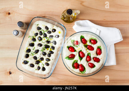 Vorbereitung der Focaccia mit Oliven und Tomaten. Rohteig in Glasscheibe links nach Sauerteig auf einem Holztisch Stockfoto